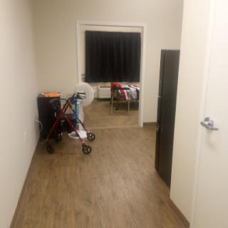 A view of a hallway leading to a room, featuring a stroller and a door.