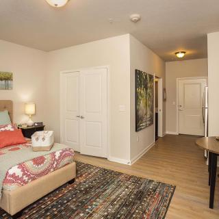 A cozy bedroom with a neatly made bed, decorative accents, and wall art.