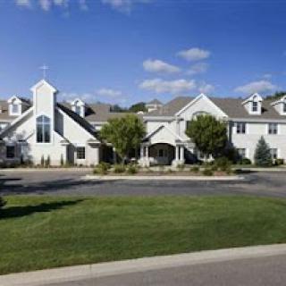 A modern residential building surrounded by well-maintained landscaping and under a clear blue sky.