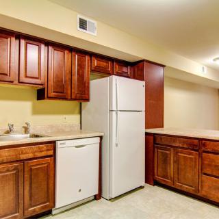 A kitchen with wooden cabinets, a white refrigerator, and a dishwasher.