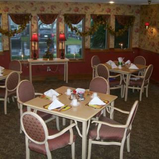 A cozy dining room setup with neatly arranged tables and chairs, decorated for a welcoming ambiance.