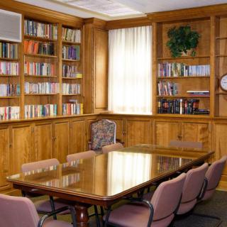 A quiet conference room with wooden bookshelves, a large table, and chairs.