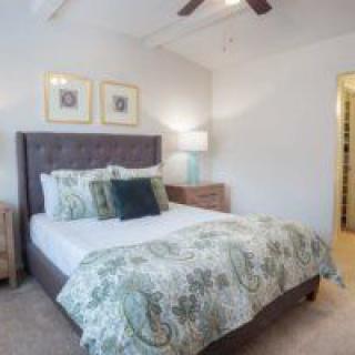 A cozy and well-decorated bedroom with a neatly made bed, accent pillows, and a stylish lamp.