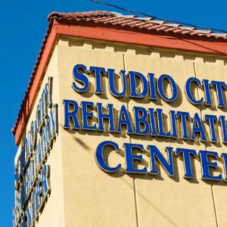 The exterior of Studio City Rehabilitation Center showing its signage against a clear blue sky.