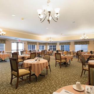 A spacious dining room with neatly arranged tables and chairs, adorned with chandeliers.