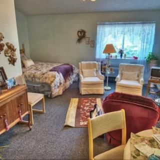 A cozy living area with a bed, comfortable chairs, and homey decor.