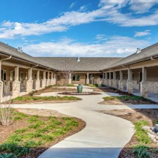 A serene courtyard with a winding pathway and landscaped gardens under a bright blue sky.