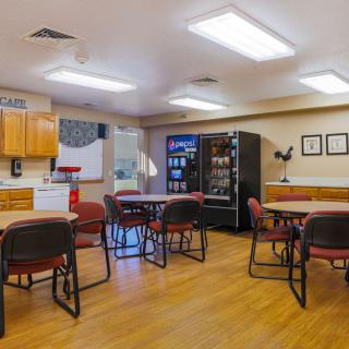 A spacious break room with tables, chairs, and a vending machine.