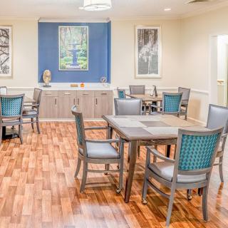 A cozy dining area with wooden floors, multiple tables and chairs, and artwork adorning the walls.