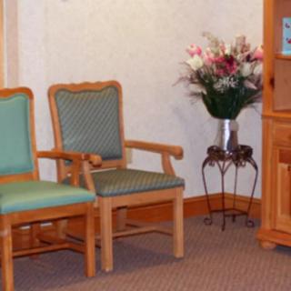 A cozy waiting room with two wooden chairs and a vase of flowers on a table.