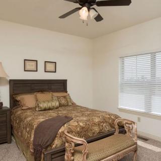 A cozy bedroom with a bed, ceiling fan, and window providing natural light.