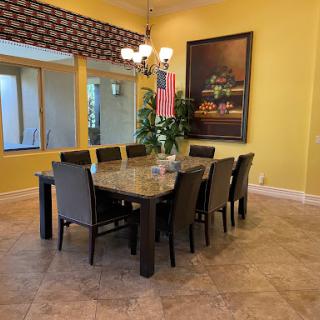 A spacious dining room featuring a large table surrounded by chairs, complemented by vibrant yellow walls and elegant lighting.