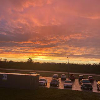A stunning sunset painting the sky in shades of orange and purple, with cars parked below.