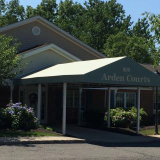 An outdoor view of a building entrance with an awning and surrounding greenery.