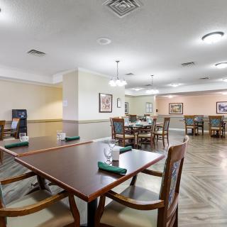 A spacious dining area with neatly arranged tables and chairs, featuring elegant lighting and wooden furnishings.