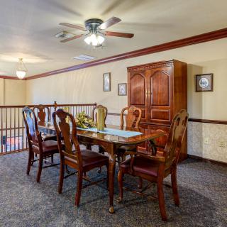 A dining area featuring a wooden table with chairs, a cabinet, and a ceiling fan.