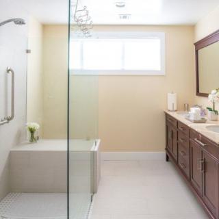 A modern and clean bathroom with a glass shower, double vanity, and large mirror.