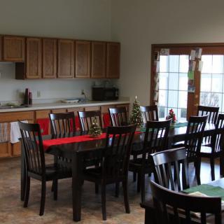 A spacious kitchen and dining area with a large table and multiple chairs, featuring wooden cabinets and glass doors.