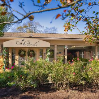 A charming home with a welcoming porch surrounded by blooming flowers and lush greenery.