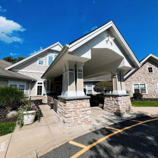 A residential building with a covered entrance and stone pillars under a clear blue sky.