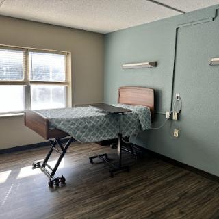A clean and simple hospital room featuring a adjustable bed and a window.