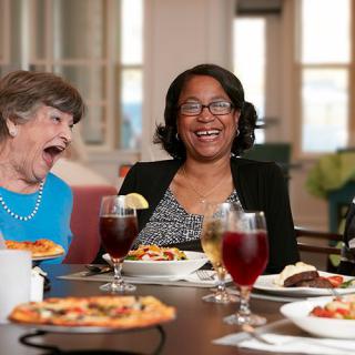 A group of friends enjoying a meal together, featuring laughter and pizza.