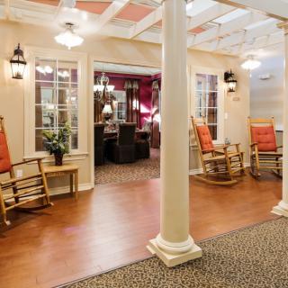 A cozy lobby with rocking chairs and warm lighting, featuring traditional design elements.
