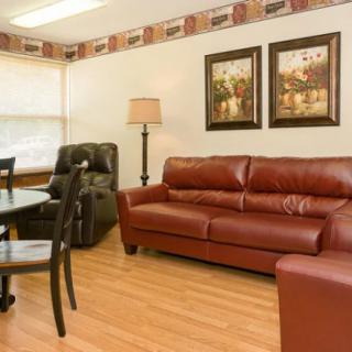A cozy living room with a leather sofa, armchair, and dining set.