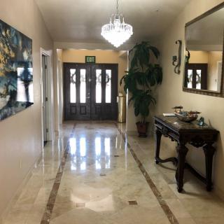 A well-decorated hallway with a chandelier, mirror, and artwork.