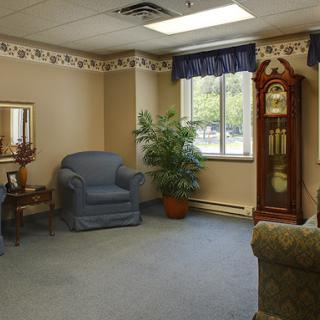 A cozy living room with comfortable furniture, a decorative clock, and a potted plant.