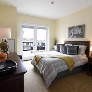 A modern bedroom with stylish decor, featuring a neatly made bed, artwork on the wall, and soft lighting.