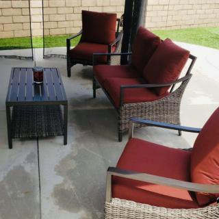 Outdoor patio furniture set with red cushions on a concrete surface.