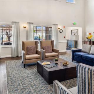 A spacious and well-furnished living room with ample seating, a central coffee table, and large windows allowing natural light.