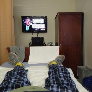 A person relaxing on a hospital bed watching television.
