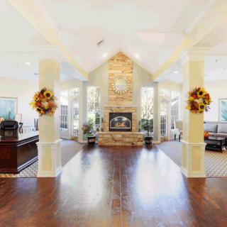A spacious and cozy living room with a central fireplace, vaulted ceiling, and abundant natural light.