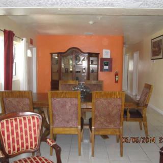 A dining room featuring a table with chairs and a cabinet set against an orange accent wall.