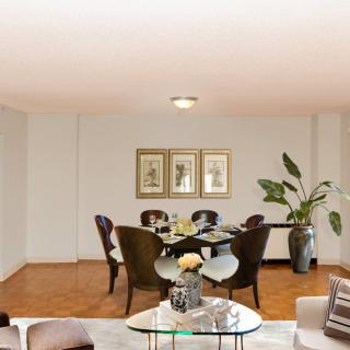 A stylish dining room with a set table, artwork on the walls, and a large plant in the corner.