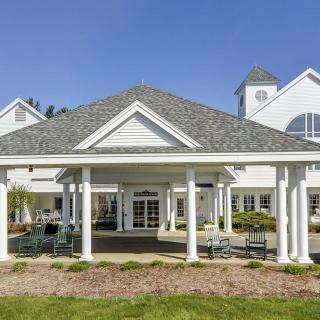 A picturesque entrance with white columns and a gabled roof, set against a clear blue sky.