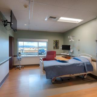 A clean and modern hospital room with a bed and medical equipment.