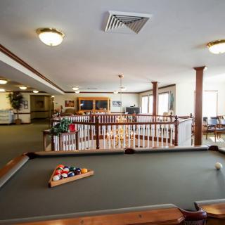 A well-lit game room featuring a pool table with balls racked and ready for play.