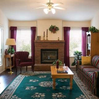 A cozy living room with a central fireplace, surrounded by comfortable furniture and warm decor.