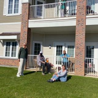 A group of people enjoying a sunny day outside a residential building with balconies.