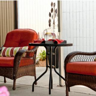 A cozy outdoor patio setting with wicker chairs and a small round table.