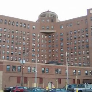 A large brick building with multiple windows, possibly a former hospital or medical facility.