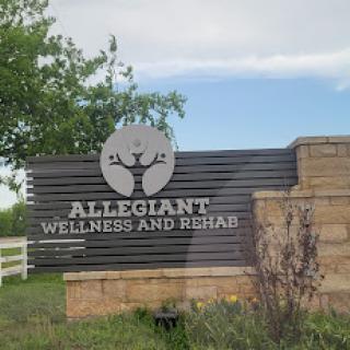 A sign for Allegiant Wellness and Rehab, surrounded by greenery.