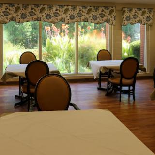 A serene dining area featuring tables and chairs with large windows allowing natural light to fill the space.