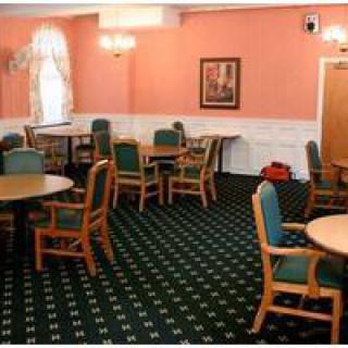 A dining area with several tables and chairs, carpeted floor, and warm-toned walls.