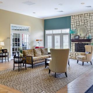 A spacious and elegantly decorated living room featuring comfortable seating, a central fireplace, and abundant natural light.