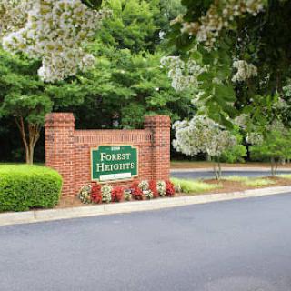 Entrance to a residential area with a brick sign and landscaped surroundings.