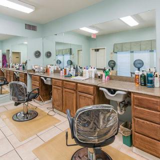 An empty hair salon with styling chairs and mirrors lined up along the counter.